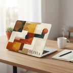 Personalized abstract geometric MacBook case with custom name Olivia in terracotta mustard navy and cream color blocks, displayed on wooden desk with coffee cup, small plant and notebook nearby — bold architectural collage hard shell laptop cover with elegant serif name personalization, Apple logo visible through an unprinted area, slim snap-on fit, for MacBook Air 13 M2 M3 M4 M5 and MacBook Pro 14 16 M3 M4 M5, modern aesthetic personalized gift for creative professionals and art lovers