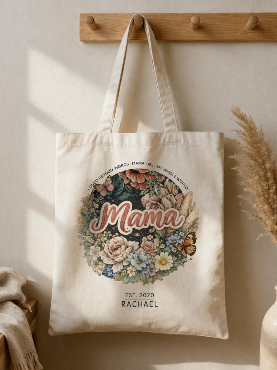 Close-up of a natural canvas tote bag, highlighting the intricate "Mama" floral wreath graphic with established year and name script.