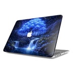 An angled profile view of a MacBook featuring a protective hardshell case with a 3D-effect design of a magical glowing blue willow tree and ethereal waterfalls against a starry night sky, with a white Apple logo visible in the center.