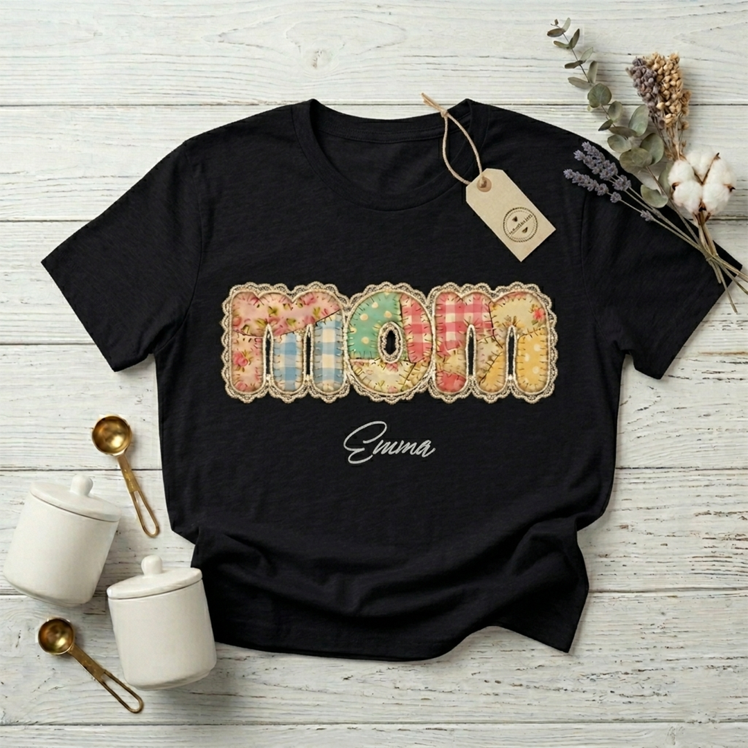Woman wearing a black personalized "Mom" T-shirt with the unique floral patchwork design against a cozy home decor background.