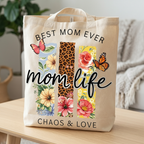 Close-up of a cream-colored "Best Mom Ever" tote bag with high-quality floral and butterfly print in a home setting.

