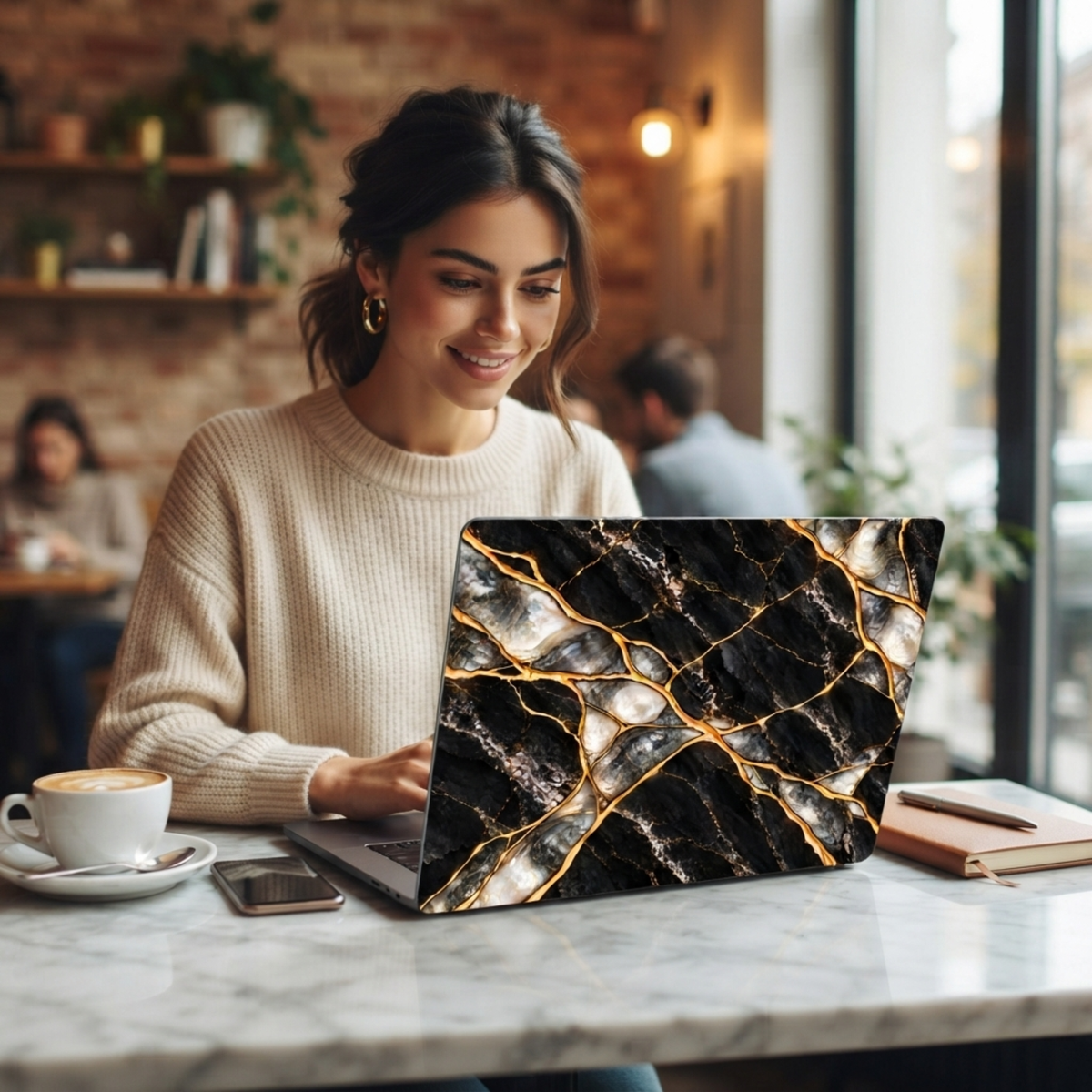 Woman in a café working at a marble table on a MacBook in a Black Pearl black marble printed case.