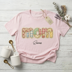 Model wearing a soft pink personalized "Mom" T-shirt, perfectly displaying the delicate quilted floral art design with name Emma script.