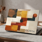 Personalized abstract geometric MacBook case with custom name Olivia in terracotta mustard navy and cream color blocks, displayed on terrazzo countertop with dried flower vase and textured wall background — bold architectural collage hard shell laptop cover with elegant serif name personalization, Apple logo visible through an unprinted area, slim snap-on fit, for MacBook Air 13 M2 M3 M4 M5 and MacBook Pro 14 16 M3 M4 M5, modern aesthetic personalized gift for creative professionals and art lovers