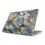 Angled view of a MacBook featuring a protective hard shell case with an intricate stained glass hummingbird design. The artwork displays two vibrant hummingbirds in shades of emerald green and turquoise hovering near delicate lilies, with iridescent mosaic patterns and gold-accented outlines creating a 3D visual effect.