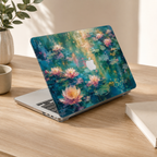 Angled view of a MacBook in a water lilies printed hard shell case on a wooden desk beside a green plant.