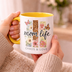Woman holding a personalized ceramic mug with a yellow handle and rim, featuring a vibrant Boho "Mom Life" graphic with butterflies and flowers.