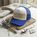 Custom blue mesh back cap mockup with a cozy quilt-style "Mom" graphic and personalized name, displayed on a rustic background.
