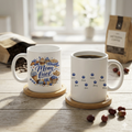 Close-up of the "Mom Fuel" mug design showing detailed watercolor croissants, cupcakes, and blueberries with the name Noah scripted below.
