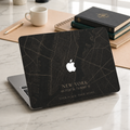 Personalized City Map MacBook case from TrioAuraDesign, shown on a light marble desk with a dark New York street map design. The hard shell features custom city text “NEW YORK,” coordinates, and the phrase “YOUR PLACE. YOUR STORY.” in warm beige lettering, with the Apple logo visible at center. Modern custom map laptop cover for compatible MacBook Air, Pro, and Neo models.