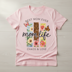 Flat lay mockup of a soft pink "Mom Life" t-shirt, displaying the colorful wildflower, leopard print, and butterfly graphic design with "Chaos & Love" text.