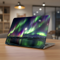 Lifestyle photo of a MacBook on a light wooden table in a modern interior. The laptop is protected by a hard shell case featuring a stunning Northern Lights design, showcasing the Aurora Borealis in vivid green and purple hues over a serene arctic landscape with a reflective lake and starry sky.
