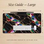 Size guide for the large black marble desk mat: 90 cm / 36 in wide and 45 cm / 18 in deep, shown from above on a wooden desk with a full-size keyboard and mouse for scale. Jewel Tone style with gold kintsugi effect veins. Also available in Medium 70 × 40 cm (28 × 16 in).
