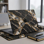Matching set: MacBook in the black marble gold vein effect hard shell case standing on the matching black marble desk mat, with a notebook and pen. Marble and gold are printed effects on smooth surfaces.