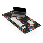 Jewel Tone black marble desk mat on a white background with a laptop, keyboard, mouse and phone, showing the full printed design with colorful opal-like stones between gold veins and stitched edges.