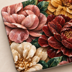 Close-up of a TrioAuraDesign Stone Bouquet MacBook case featuring blush pink, deep burgundy, ivory and warm golden flowers with dark green leaves and a printed marble stone effect. The detailed floral artwork fills the laptop cover, shown at an angle on a soft beige background with the smooth case edge visible.