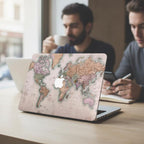 Vintage world map MacBook case on cafe table with two people in background, antique cartographic laptop cover for travelers and adventurers