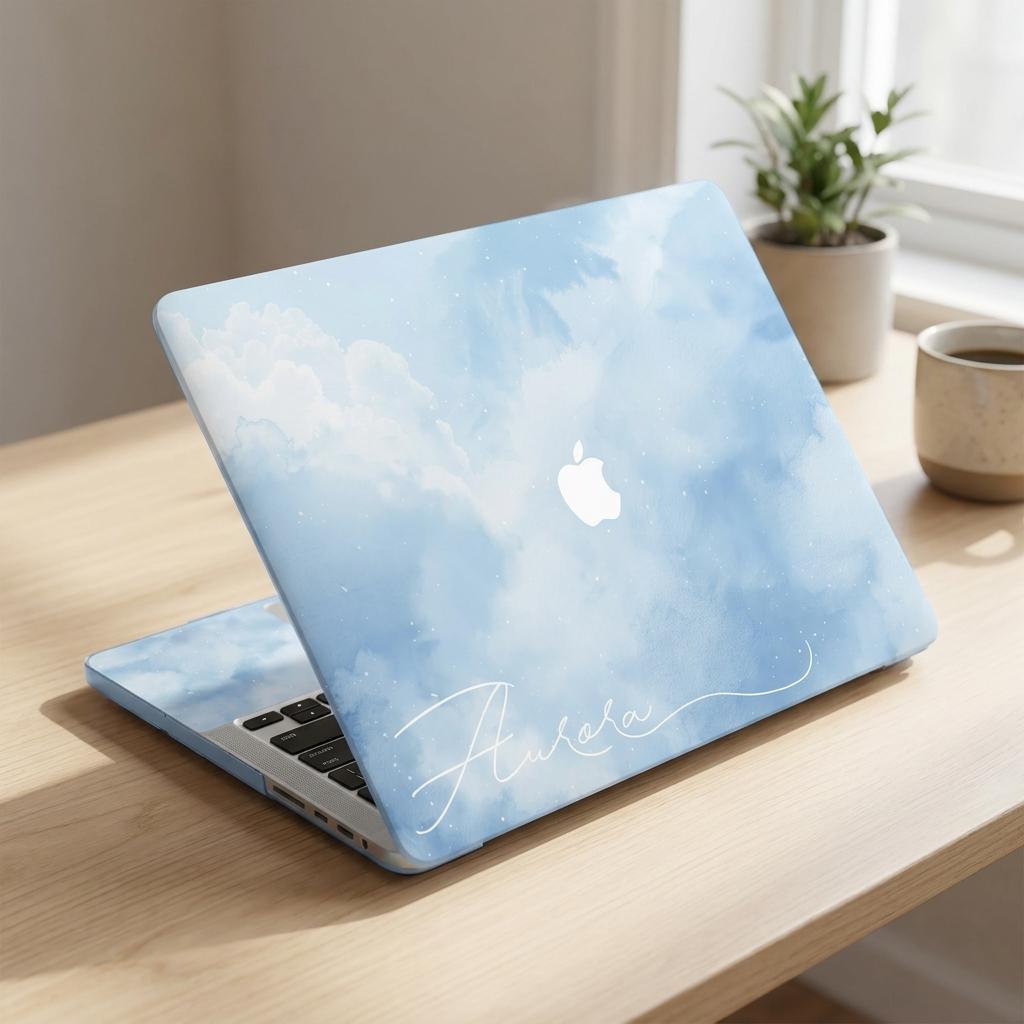 Custom name MacBook case with soft blue watercolor sky and cloud print, personalized with white signature script name Aurora, lifestyle photo on wooden desk with plants