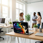 Colorful paint splash MacBook case on office desk, abstract rainbow laptop cover with custom initials, bright modern workplace with people in background