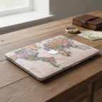 Vintage world map MacBook case on wooden desk with compass and travel maps, antique cartographic laptop cover in rose and sage tones