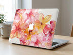 Watercolor hibiscus MacBook case on desk with mug and plant, pink coral floral hard shell laptop cover, warm natural light