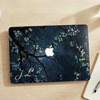 Custom initial MacBook case with dark navy botanical floral design, personalized with white script initials J.L., flat lay top view on wooden desk with notebook and pen