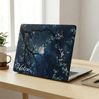 Custom name MacBook case with dark navy botanical floral design, personalized with white script name Helen, lifestyle photo on wooden desk with plants and notebook in bright home office