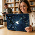 Custom initial MacBook case with dark navy botanical floral design, personalized with white script initials J.L., lifestyle photo of smiling woman holding laptop in library setting