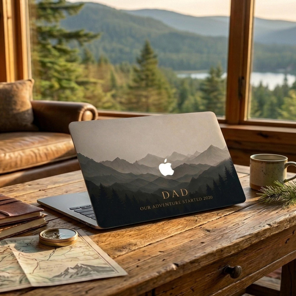 Personalized dark mountain landscape MacBook case with custom text DAD and date on rustic wooden desk with compass, map and coffee — moody forest silhouette hard shell laptop cover with misty grey gradient mountains, gold personalized inscription, Apple logo cutout, slim snap-on fit, for MacBook Air 13 M2 M3 M4 M5 and MacBook Pro 14 16 M3 M4 M5, personalized Father's Day gift for dad, adventure nature aesthetic laptop accessory