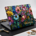 Personalized Colorful Garden MacBook case on dark leather with a brass magnifying glass and dried botanical stems.