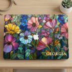 Flat lay of the Colorful Garden MacBook case with Georgia on light wood beside a white succulent pot and charging cable.