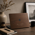 Personalized dark brown wood grain effect MacBook case from TrioAuraDesign, featuring custom text “MR. & MRS.” with “Est. 2026” below and the Apple logo visible at center. The rich walnut wood look and lettering are professionally UV printed on a smooth polycarbonate hard shell, not real wood or engraving. Customizable with a name, family title, year, or short phrase for compatible MacBook Air, Pro and Neo models.