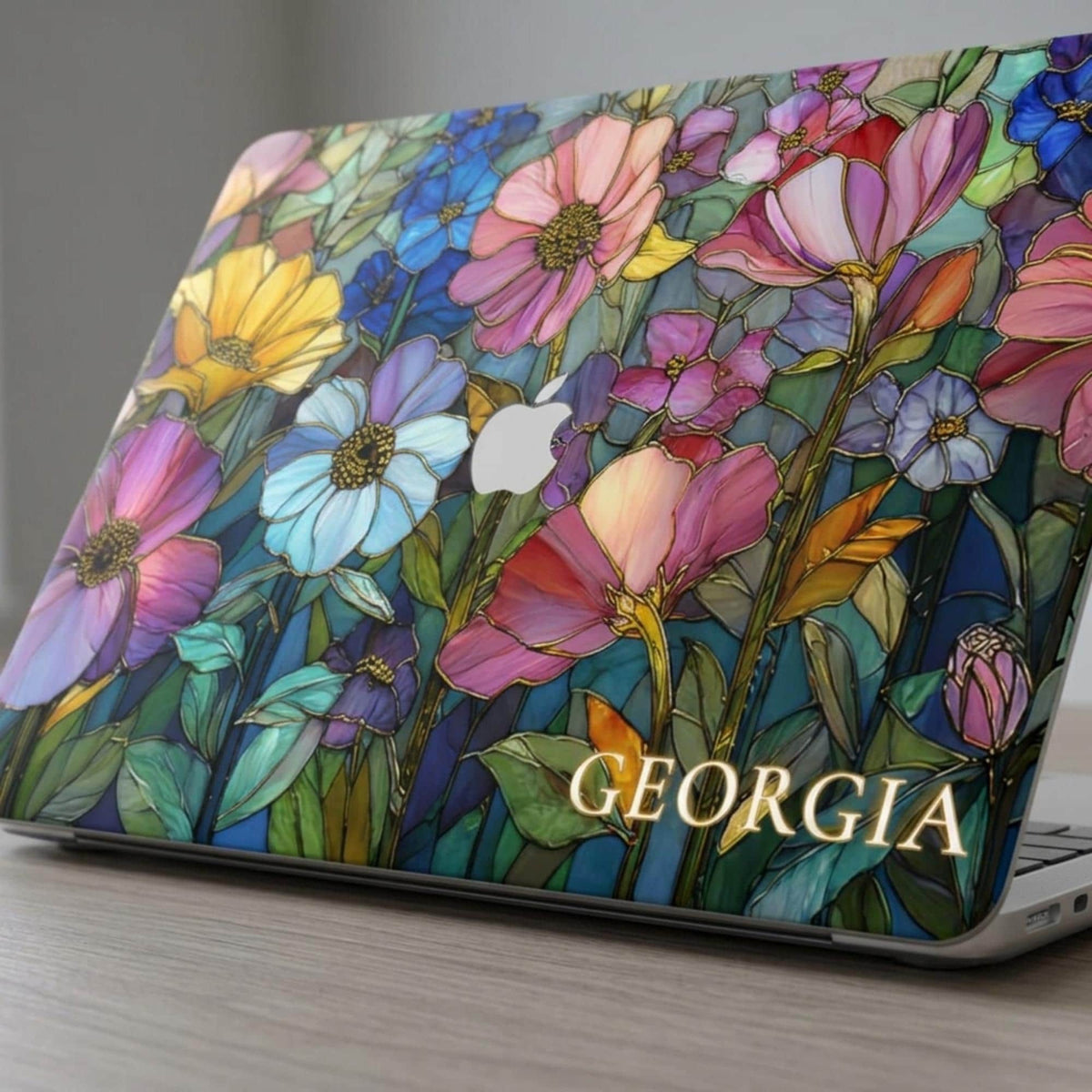 Colorful Garden stained glass effect MacBook case with the name GEORGIA in gold lettering at the bottom right and the Apple logo area in the center.
