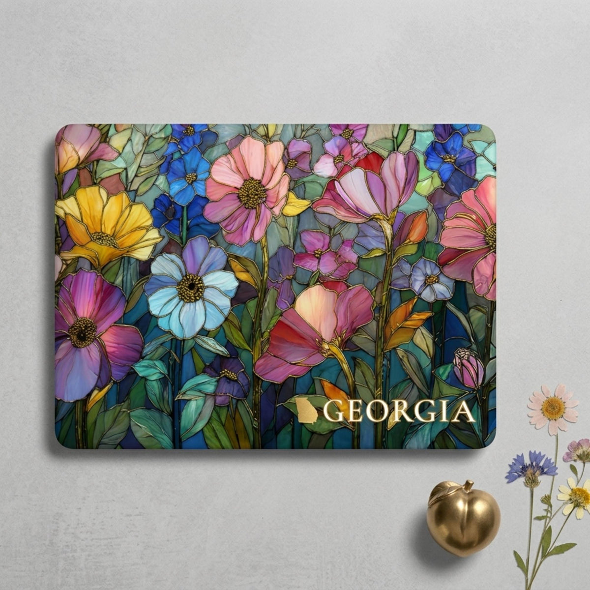 Top view of a MacBook case personalized with the name Georgia: colorful stained glass effect wildflowers in pink, blue, purple, yellow and coral with gold-look outlines on a dark background. Printed effect, smooth matte finish.
