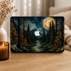 Personalized stained glass effect MacBook hard shell case featuring a dark autumn forest, glowing full moon, blue mountains, golden fall leaves and a winding path, with the Apple logo visible in the center. Custom name laptop cover for MacBook Air 13 15, MacBook Pro 13 14 16 and MacBook Neo. Nature-inspired fall case by TrioAuraDesign shown in a cozy neutral home setting.