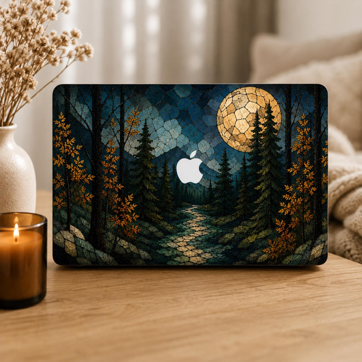Personalized stained glass effect MacBook hard shell case featuring a dark autumn forest, glowing full moon, blue mountains, golden fall leaves and a winding path, with the Apple logo visible in the center. Custom name laptop cover for MacBook Air 13 15, MacBook Pro 13 14 16 and MacBook Neo. Nature-inspired fall case by TrioAuraDesign shown in a cozy neutral home setting.
