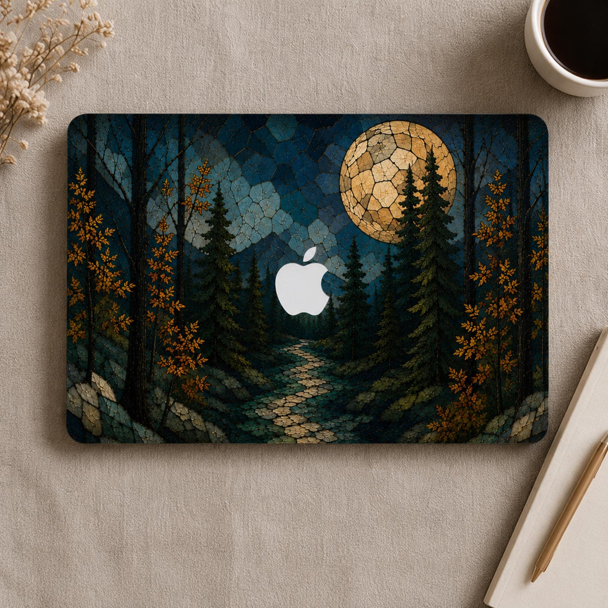 Personalized stained glass effect MacBook hard shell case shown from above, featuring a dark evergreen forest, golden autumn leaves, blue mountains, winding path and glowing full moon, with the Apple logo visible in the center. Custom fall laptop cover for MacBook Air 13 15, MacBook Pro 13 14 16 and MacBook Neo. Nature-inspired personalized case by TrioAuraDesign.