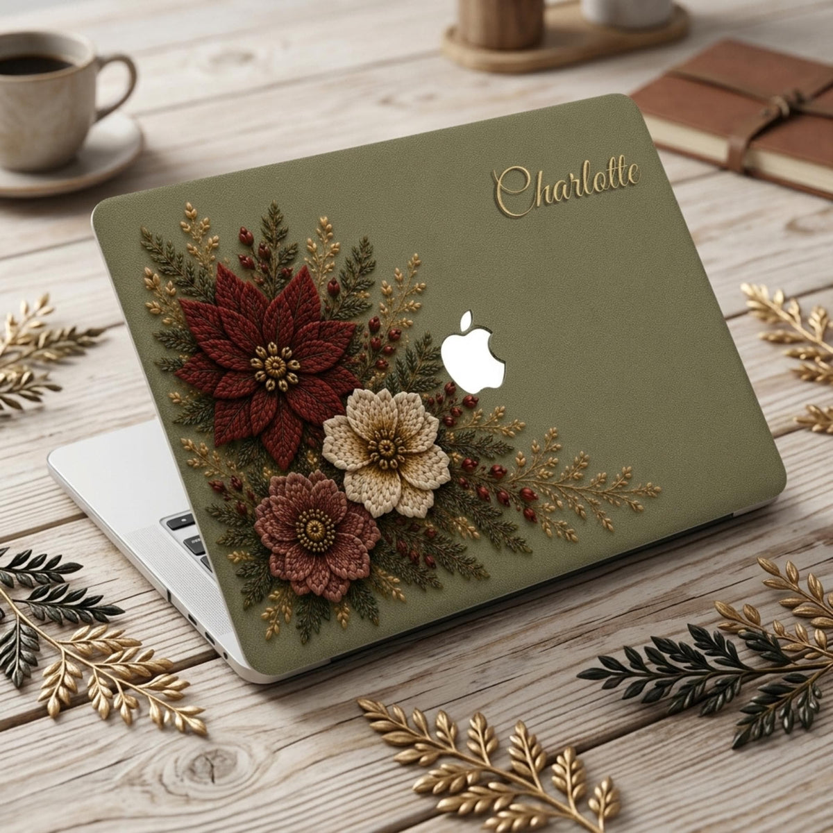 Personalized sage green Crochet effect floral MacBook case from TrioAuraDesign, featuring deep burgundy, ivory and dusty rose flowers with botanical greenery, red berries and gold-toned details. Custom name “Charlotte” appears in elegant gold script at the upper right, with the Apple logo visible at center. Smooth printed hard shell laptop cover with a rich botanical look, available in my shop for MacBook Air, Pro and Neo models.