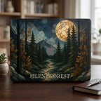 Personalized stained glass effect MacBook hard shell case featuring a dark evergreen forest, golden autumn leaves, blue mountains, winding path and large glowing full moon. “SILENT FOREST” is printed in light serif lettering across the bottom, with the Apple logo area visible in the center. Custom fall laptop cover for MacBook Air 13 15, MacBook Pro 13 14 16 and MacBook Neo. Nature-inspired case by TrioAuraDesign.