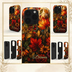 Personalized autumn stained glass effect iPhone case from TrioAuraDesign, shown in use during a phone call at a leafy café. The smooth printed case features glowing maple leaves, berries and florals in burnt orange, deep red, golden yellow and olive tones, creating a rich stained glass mosaic look. Artistic fall phone case with custom personalization, available in my shop.