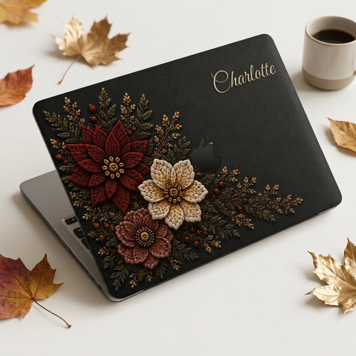 Personalized charcoal Crochet effect floral MacBook case from TrioAuraDesign, featuring deep burgundy, ivory and dusty rose flowers with dark botanical greenery, red berries and gold-toned details on a rich black background. Custom name “Charlotte” appears in elegant gold script at the upper right, with the Apple logo visible at center. Smooth printed hard shell laptop cover with a dramatic floral look, available in my shop for MacBook Air, Pro and Neo models.