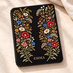 Personalized black Kindle Paperwhite case with embroidery effect wildflowers in burgundy, blue, ivory and gold, with the name EMMA printed in antique gold at the bottom of the front cover